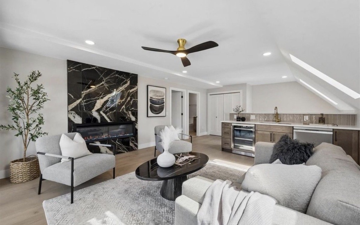 Bonus room with a black marble accent wall, wet bar, gray sectional and round marble coffee table