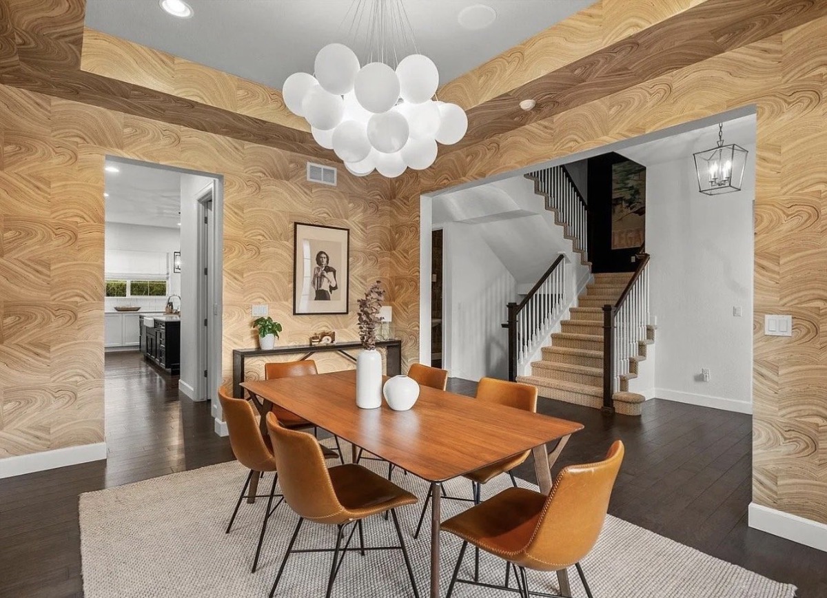 Dining room with gold marbled wallpaper, a bubble chandelier and cognac leather dining chairs