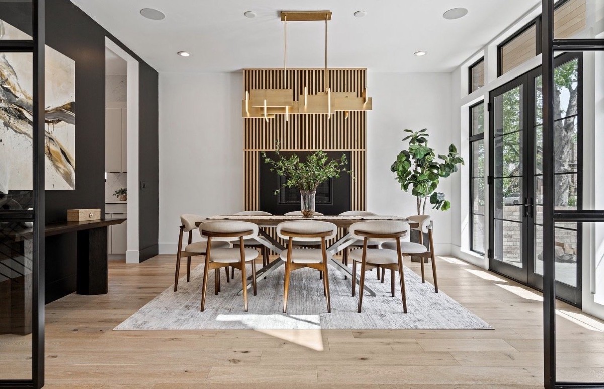 Dining room with a slatted wood feature wall, linear brass chandelier, oak chairs and steel-framed glass doors