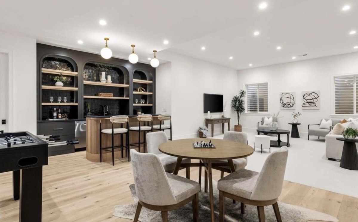 Game room with arched black built-in bar shelving, counter stools, card table and foosball