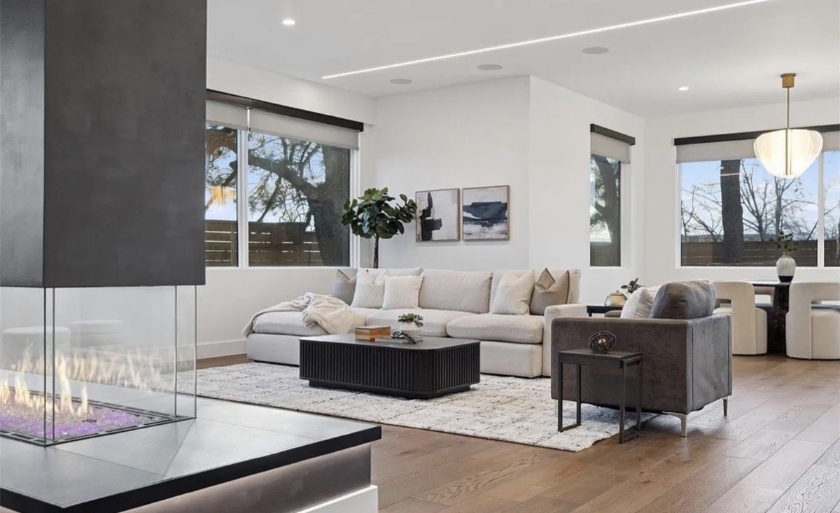 Contemporary living room with a see-through glass fireplace, cream sectional and black coffee table