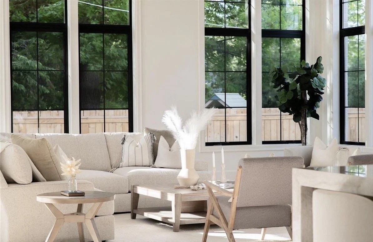 Sunlit sitting area with black-framed windows, a cream sofa, oak side tables and pampas grass in a white vase